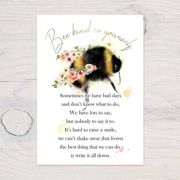 Bee kind wall art print featuring a bumblebee with floral accents and an inspirational quote on a white wood background